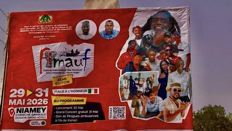Photographie détaillée du panneau d'affichage rouge du festival FIMAUF 2026 à Niamey, incluant les logos des ministères parrains, les dates, un collage d'artistes avec Barakina, et la mention du don de pirogues ambulances à l'île de Kanazi.