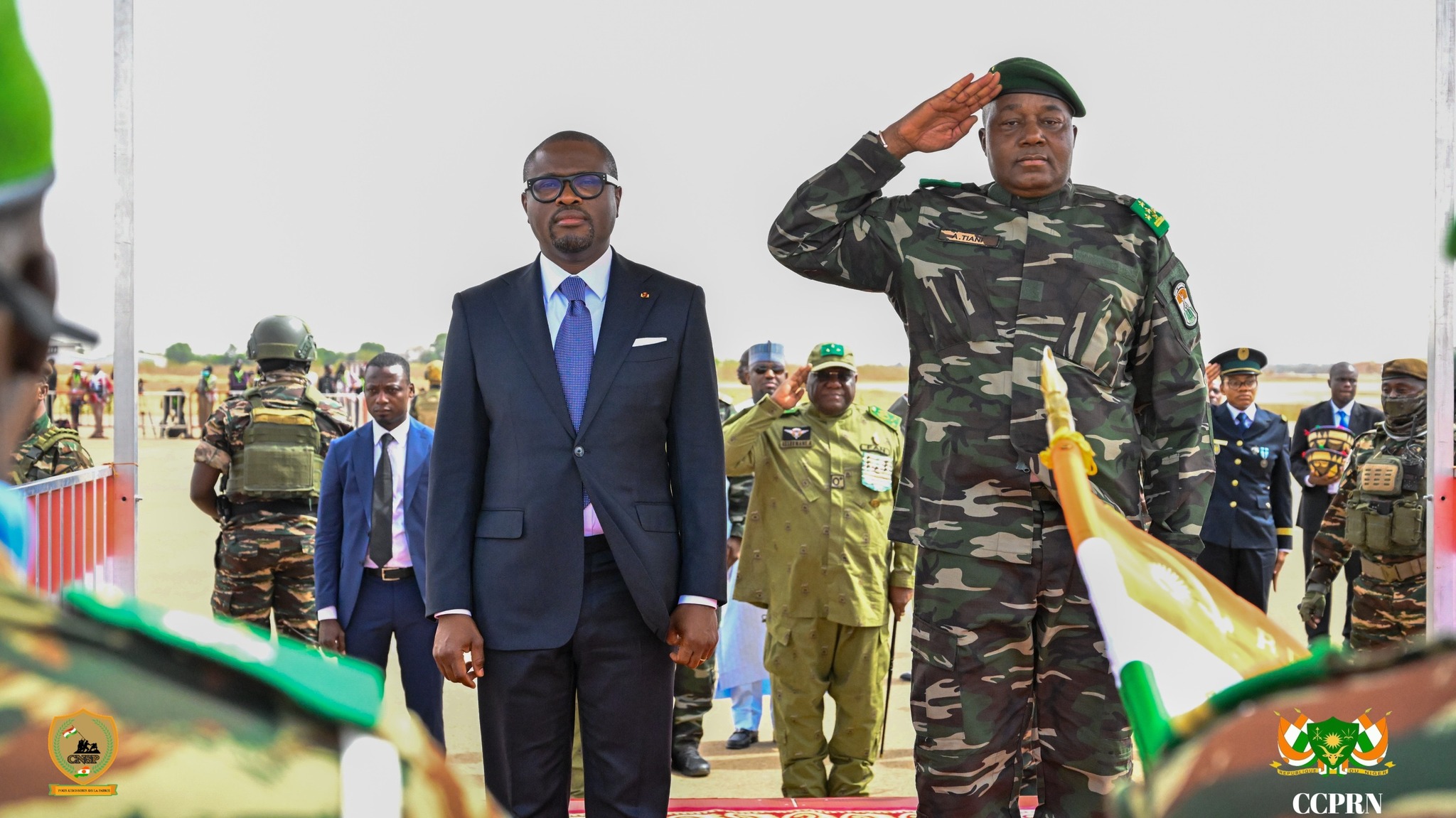Le Président du Bénin Romuald Wadagni en costume et le Président du Niger, le Général Abdourahamane Tiani en tenue militaire effectuant un salut national, debout côte à côte sur le tapis rouge à Niamey.