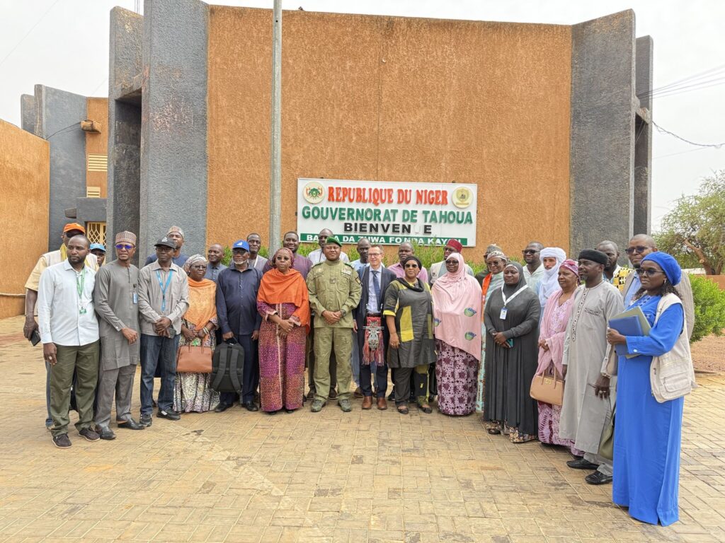 Photo de groupe officielle devant le bâtiment du Gouvernorat de Tahoua au Niger, réunissant Brian J. Williams (PBSO/PBF), le Gouverneur en tenue militaire, et la délégation de la HACP, des Nations Unies et des ONG partenaires pour la consolidation de la paix.