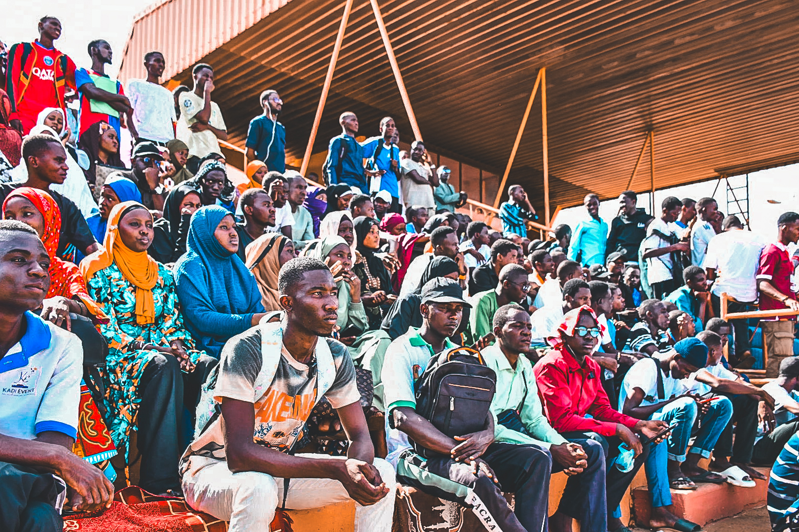 Une foule compacte d'étudiantes et d'étudiants nigériens assis dans les tribunes ombragées du Stade Municipal de Niamey, suivant attentivement la cérémonie d'ouverture des Universiades 2026.
