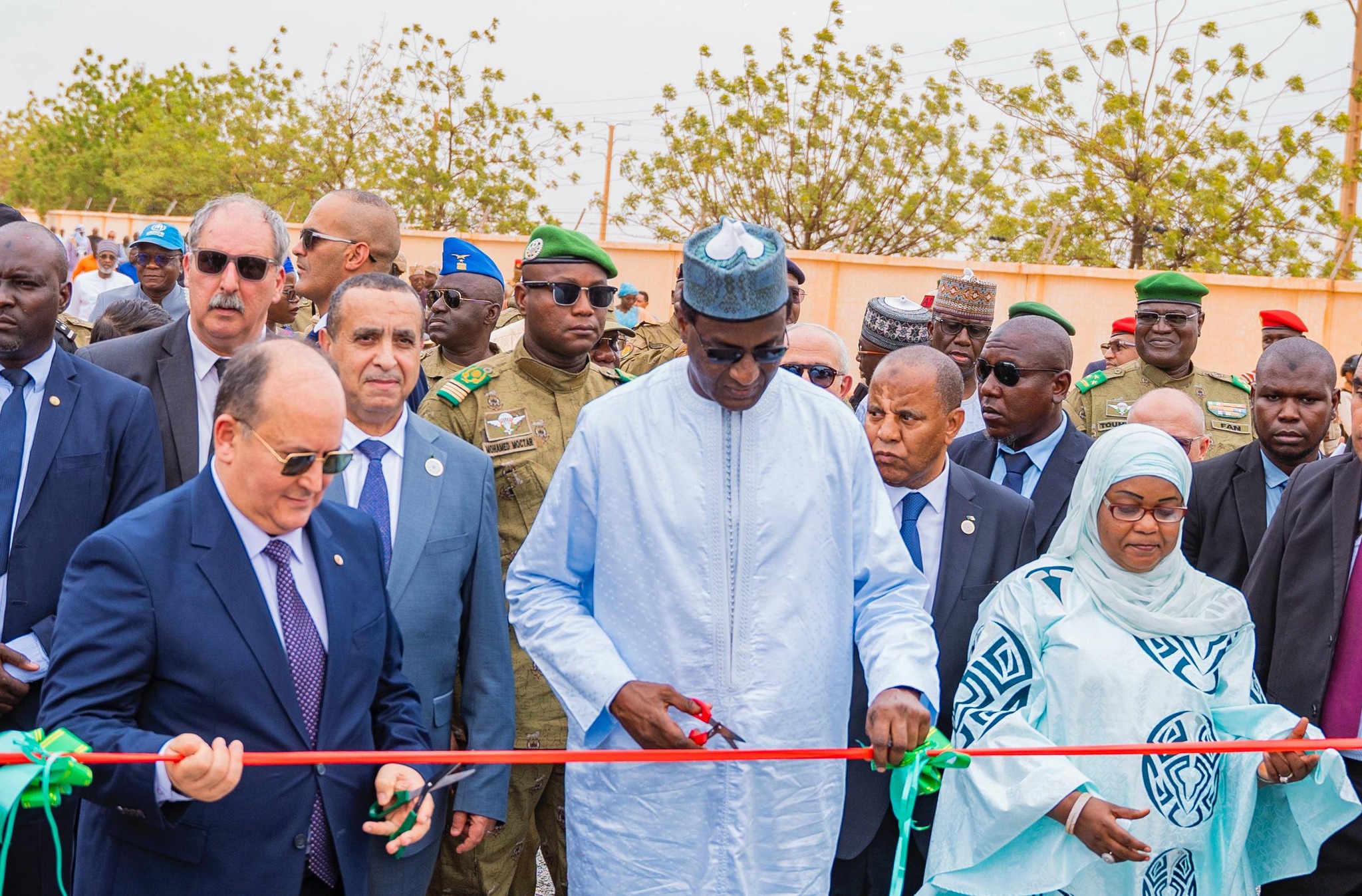 Photographie de la cérémonie d'inauguration montrant le Premier ministre nigérien (en bleu clair) et son homologue algérien (en costume marine) coupant un ruban rouge et vert. Au premier plan, une plaque commémorative en marbre porte l'inscription gravée : 'CENTRALE ÉLECTRIQUE DE SOLIDARITÉ ALGÉRO-NIGÉRIENNE - INAUGURÉE LE 3 JUIN 2026'. Le groupe d'officiels est entouré de militaires et de civils.
