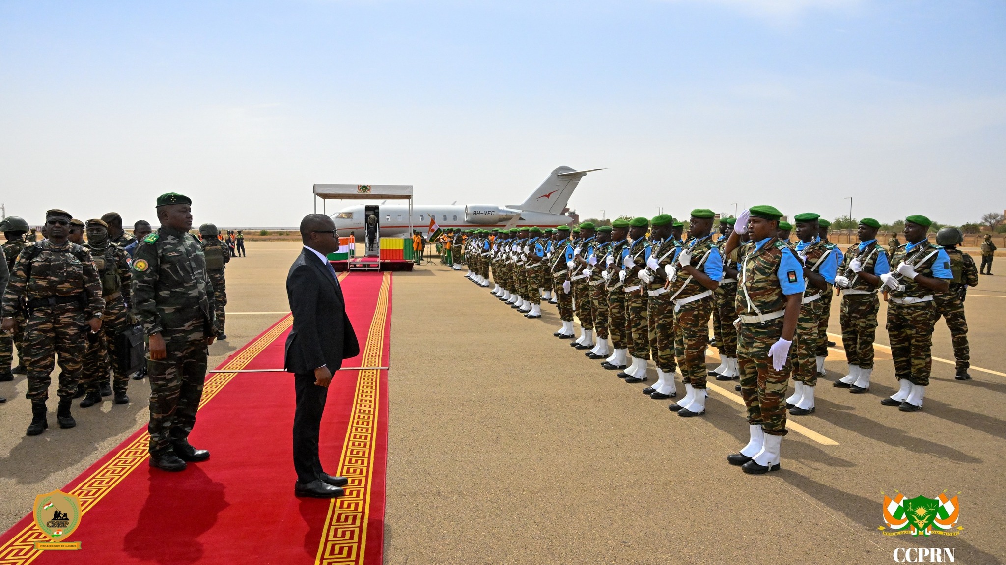 Le Président béninois Romuald Wadagni en costume noir sur le tapis rouge de l'aéroport de Niamey, faisant face à une haie d'honneur militaire nigérienne au garde-à-vous, en présence d'officiels en uniforme.